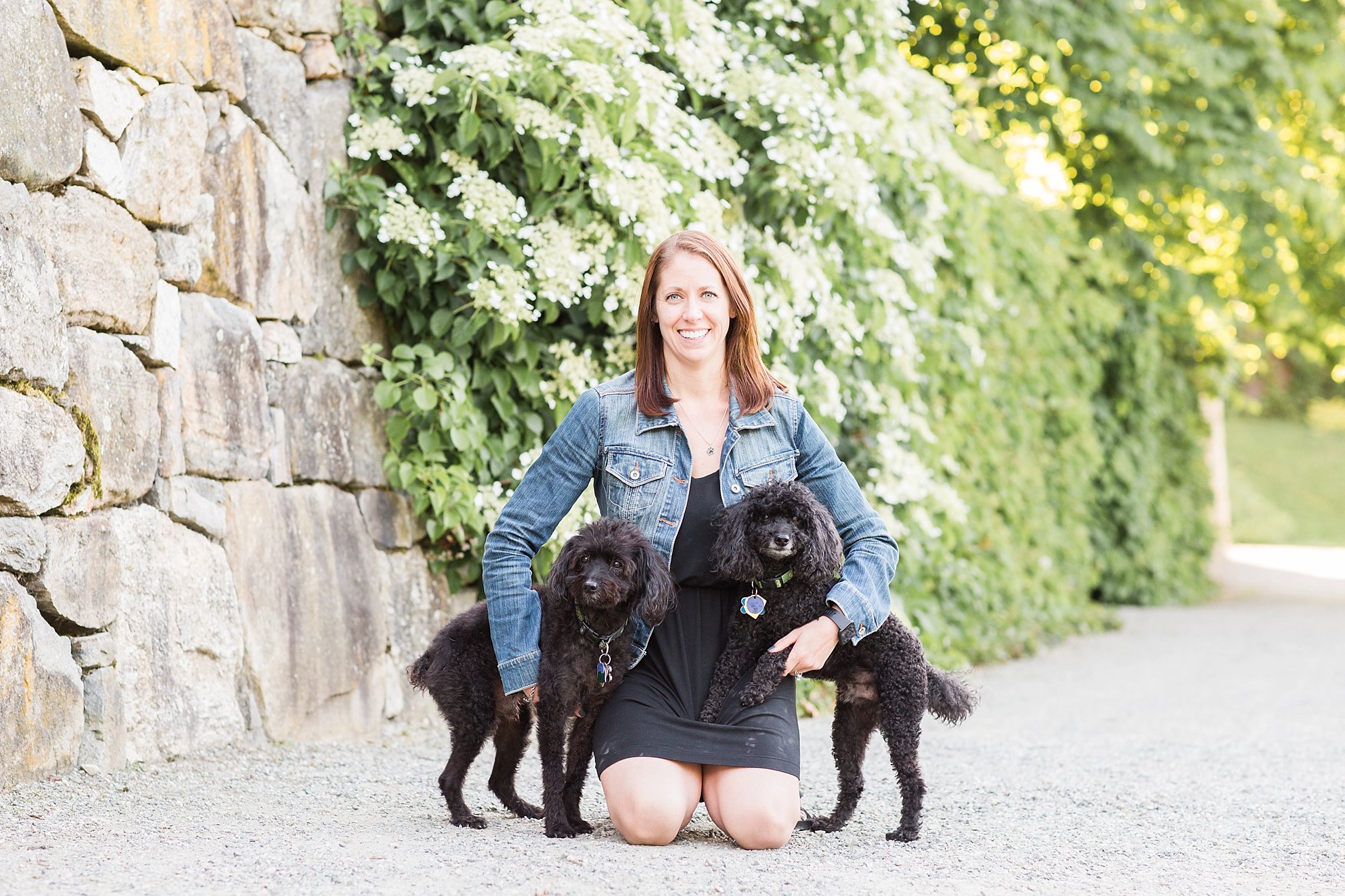 woman holding her two black yorkipoos in the Arnold Arboretum in Jamaica Pond, MA
