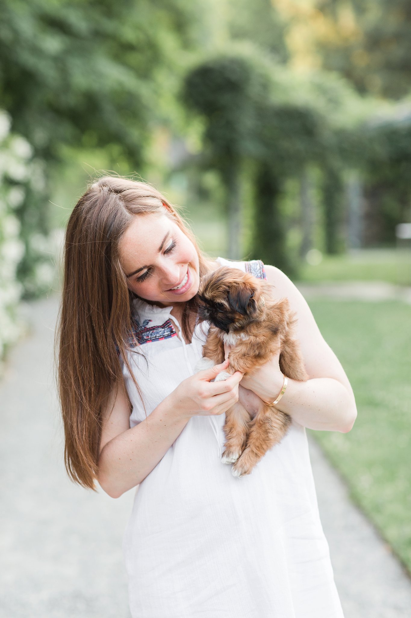 woman holding her shih tzu puppy in the Arnold Arboretum in Jamaica Pond, MA