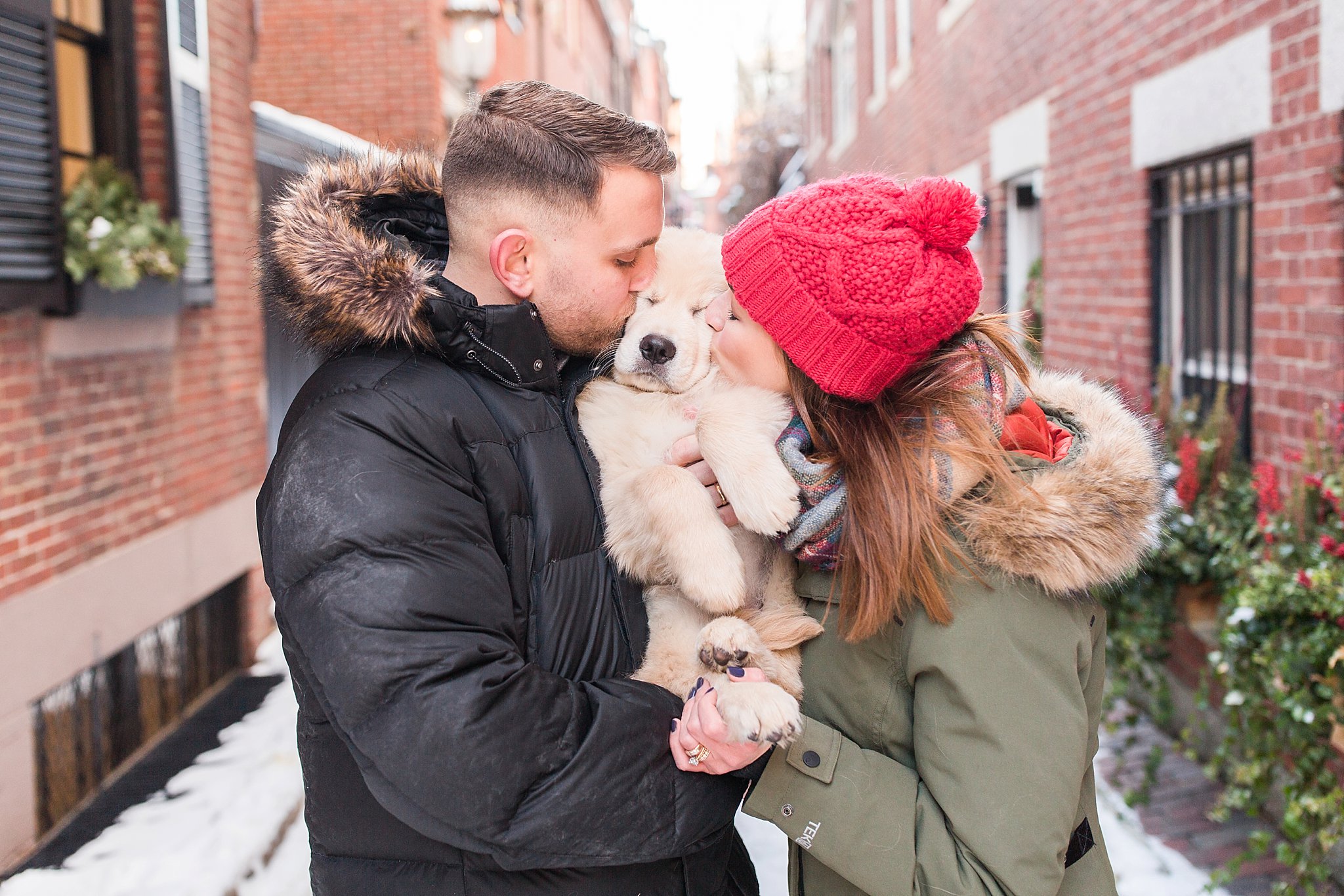 two people kissing a golden retriever puppy in the streets of Beacon Hill, Boston