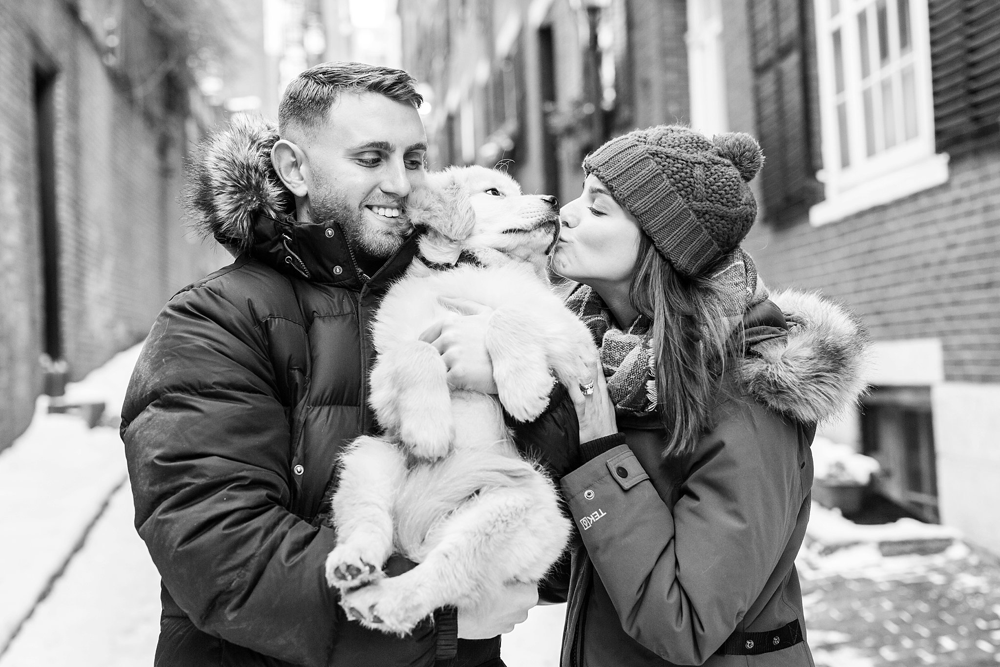 couple kissing their golden retriever puppy in the streets of Beacon Hill, Boston