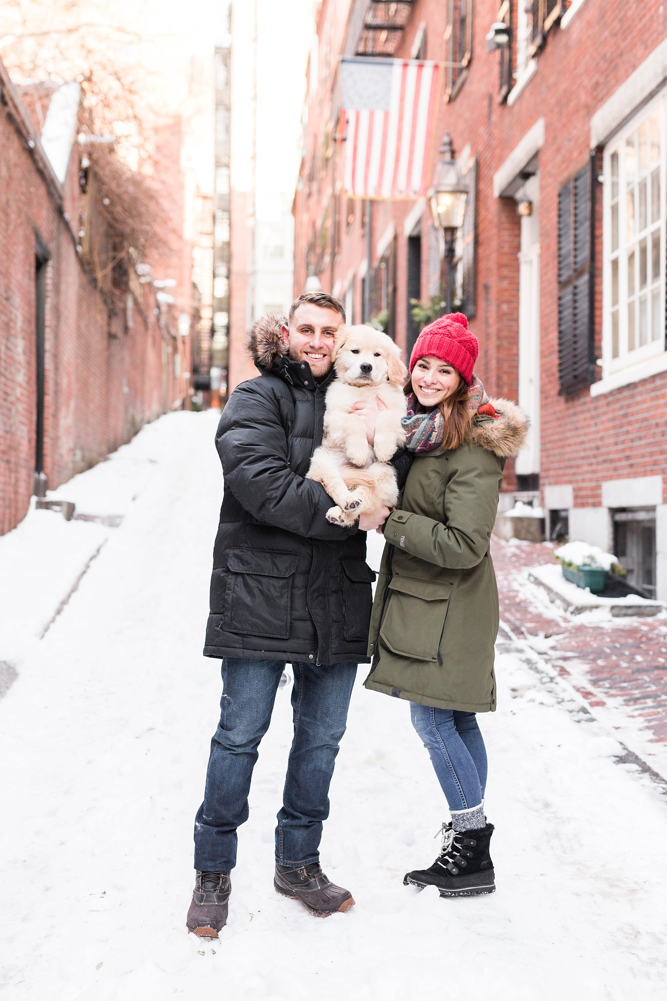 couple holding a golden retriever in the snowy streets of Beacon Hill, Boston MA