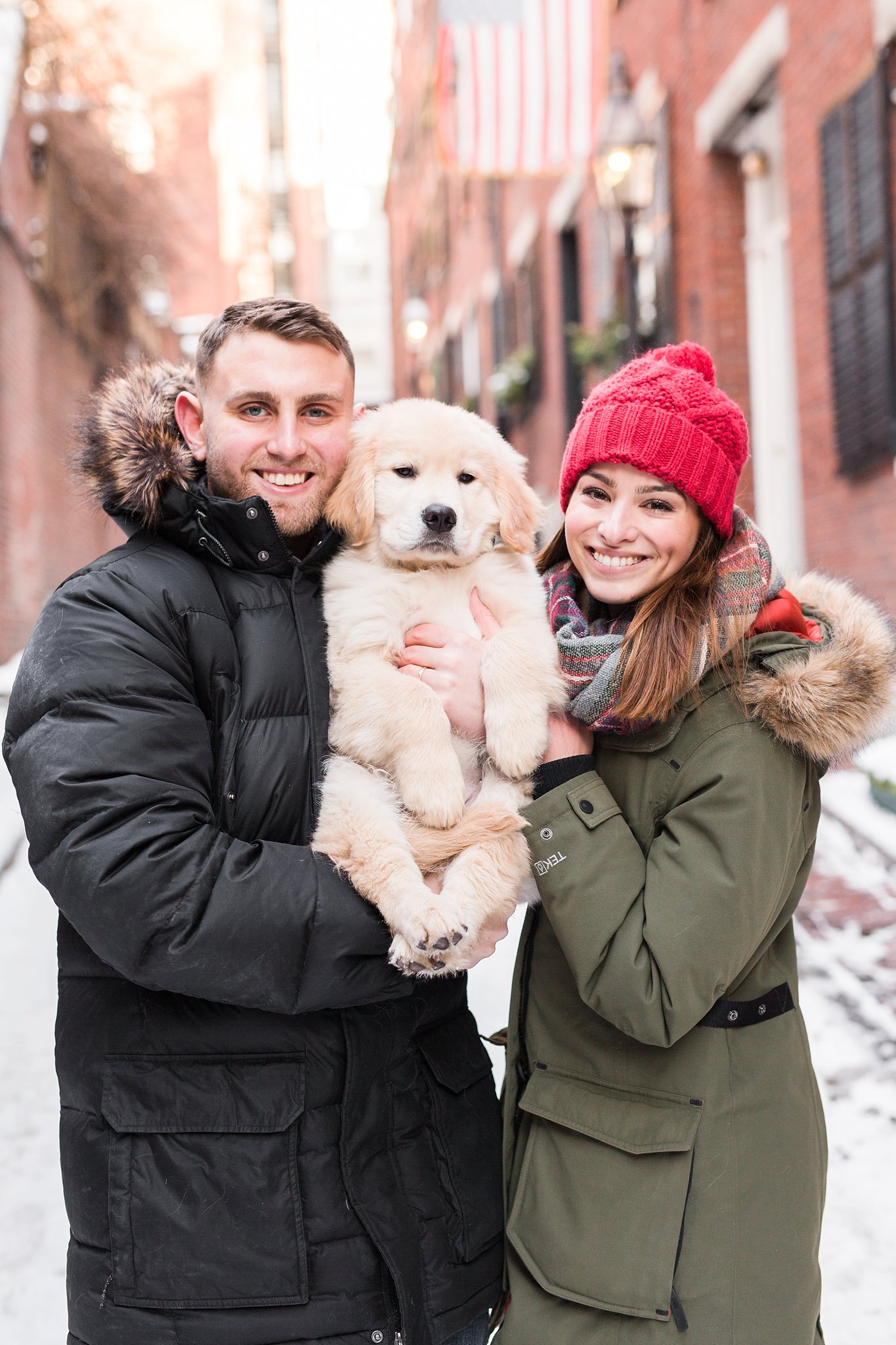 couple holding a golden retriever puppy in the snowy streets of Beacon Hill Boston