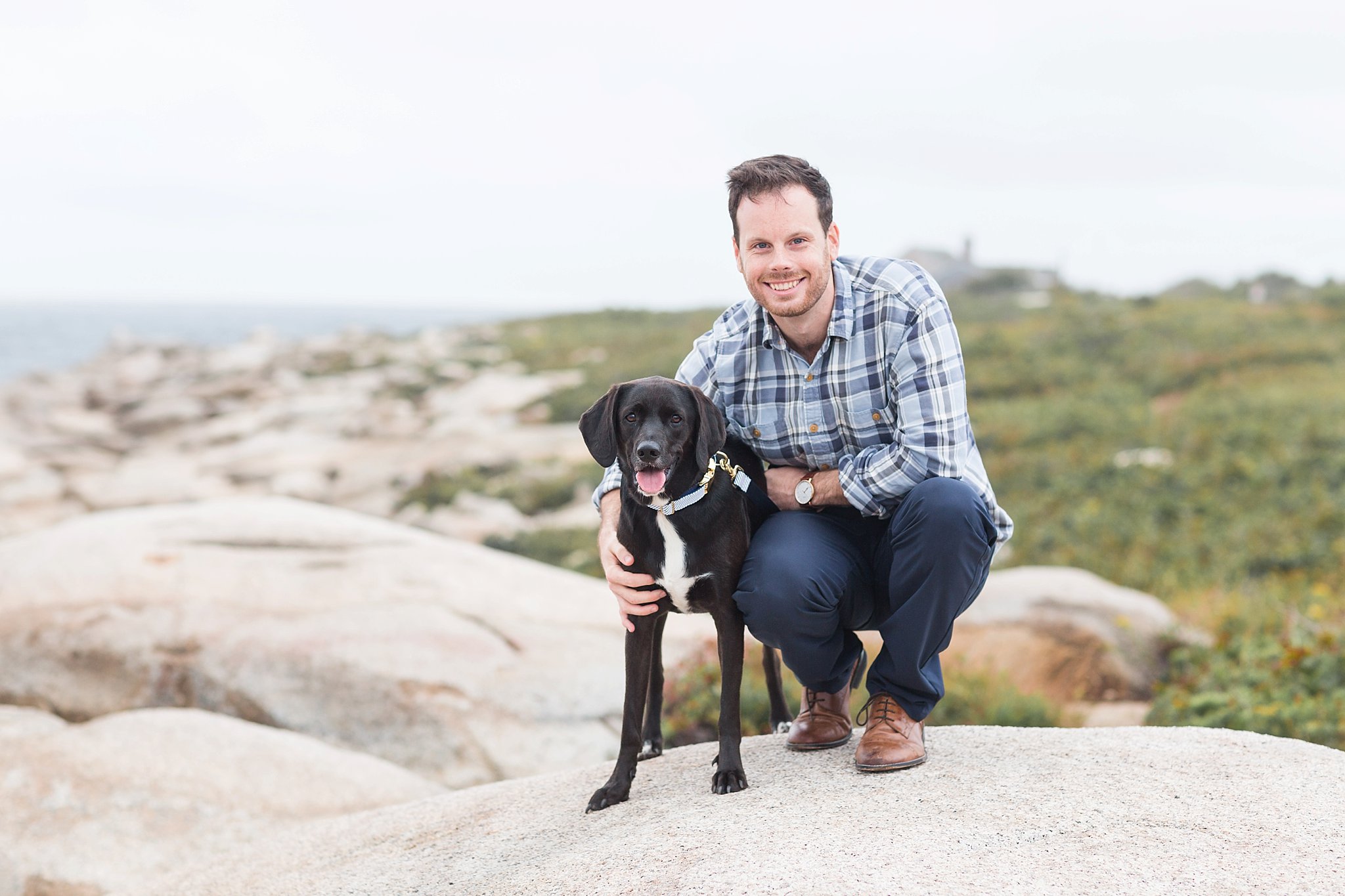 a man holding his black dog at halibut point state park