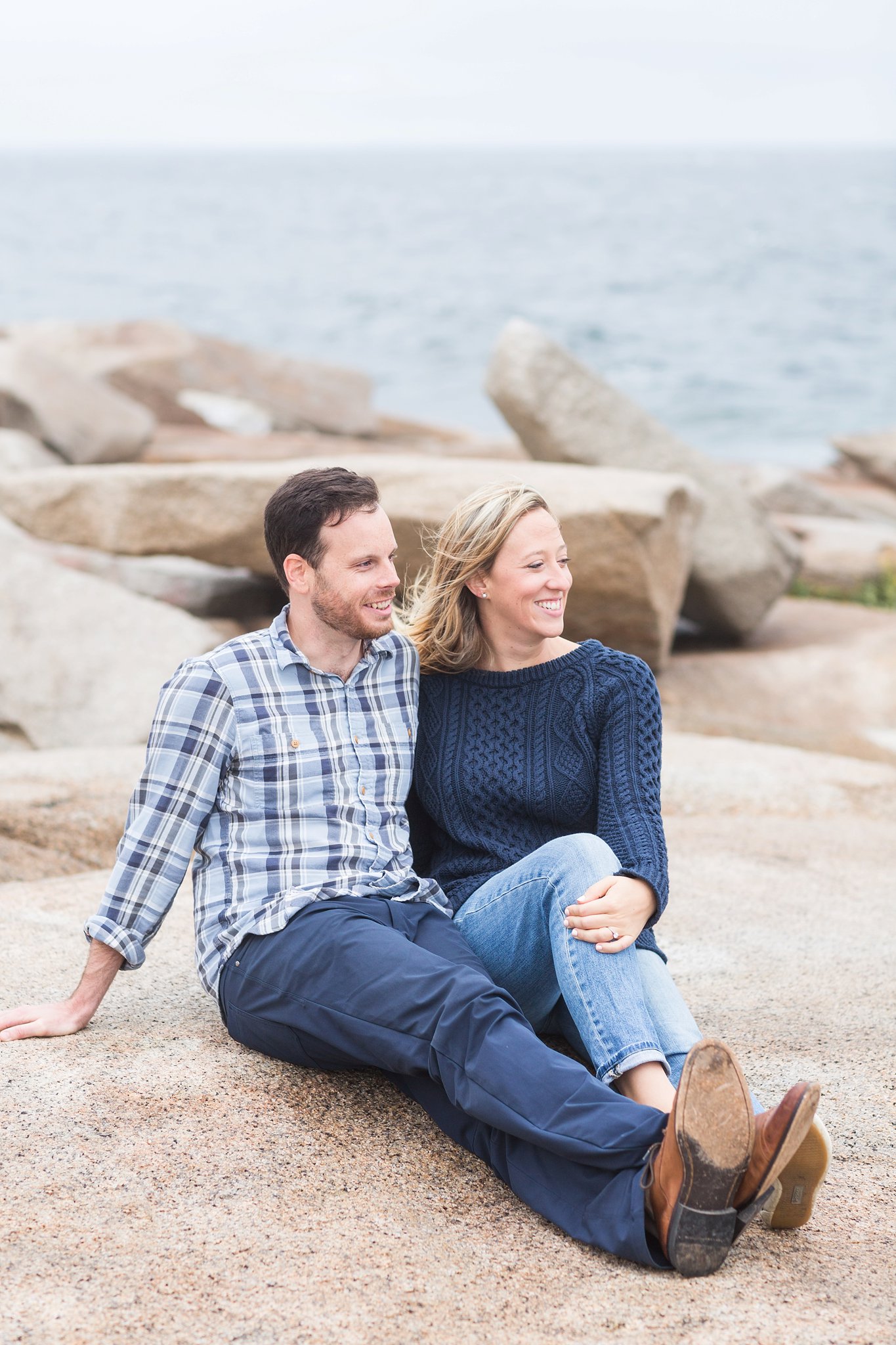 a man and woman sitting on the rocks at halibut point state park