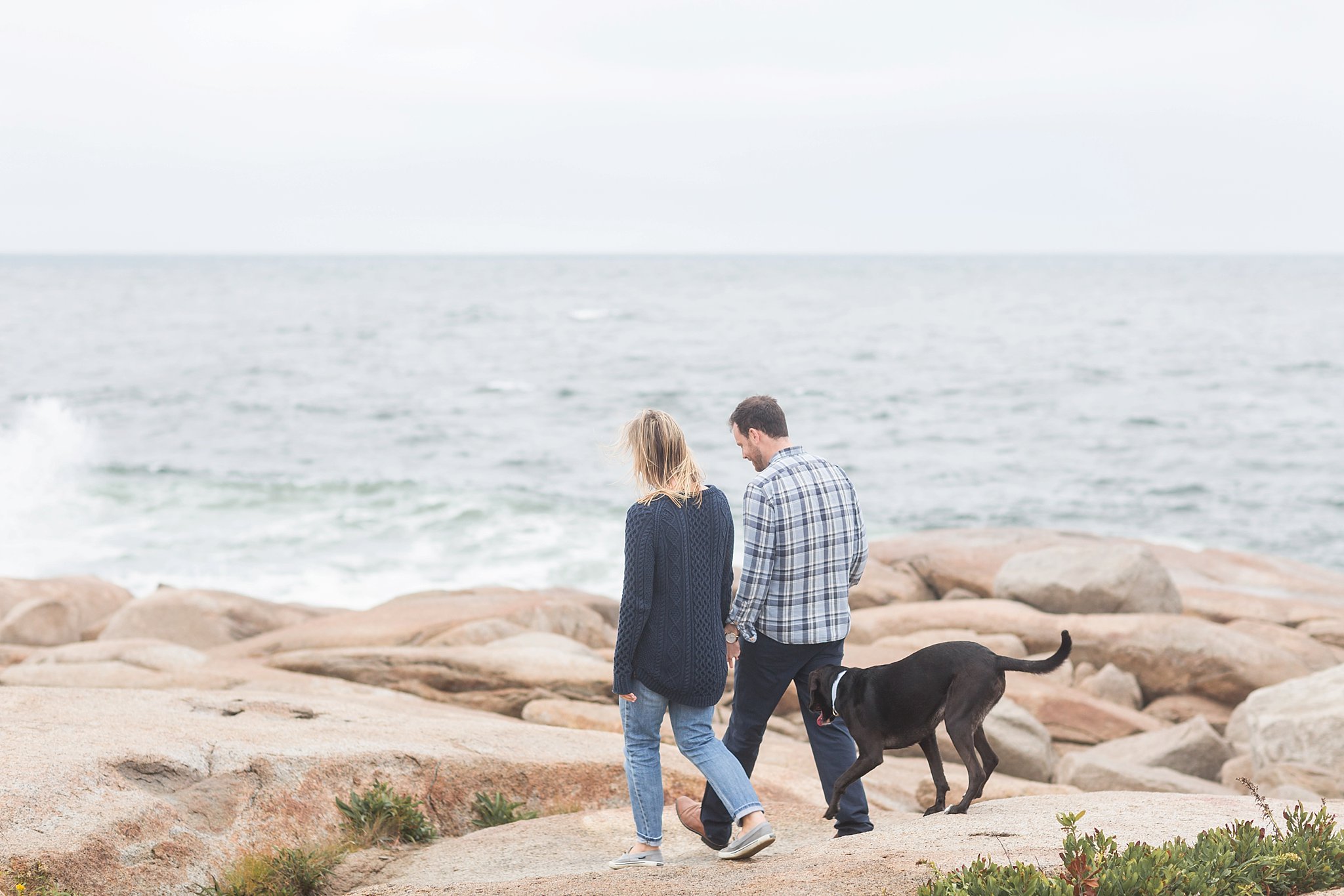 a man and woman and their dog walking on the rocks at halibut point state park