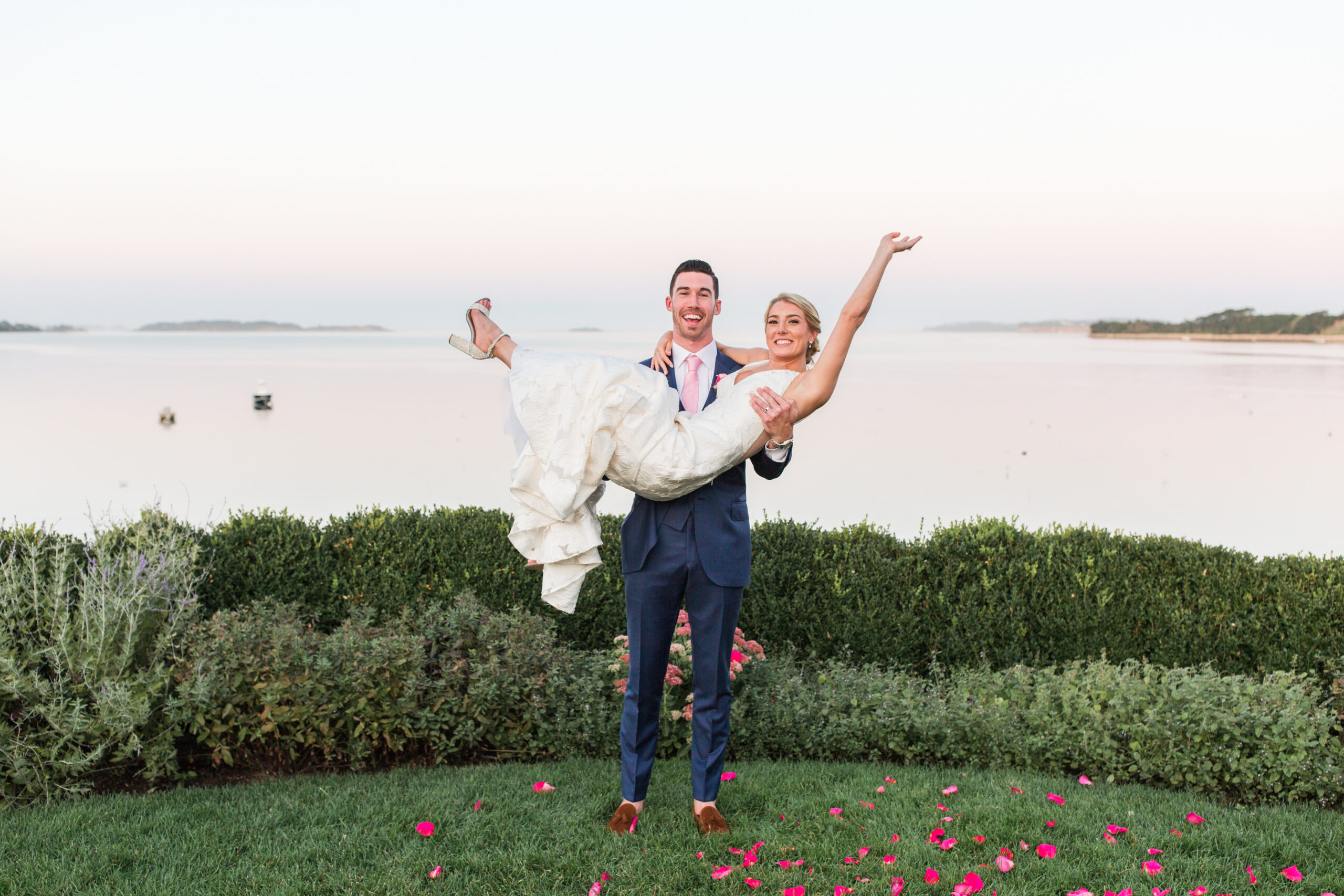 Grrom holding bride in front of water at Cape Cod wedding venue