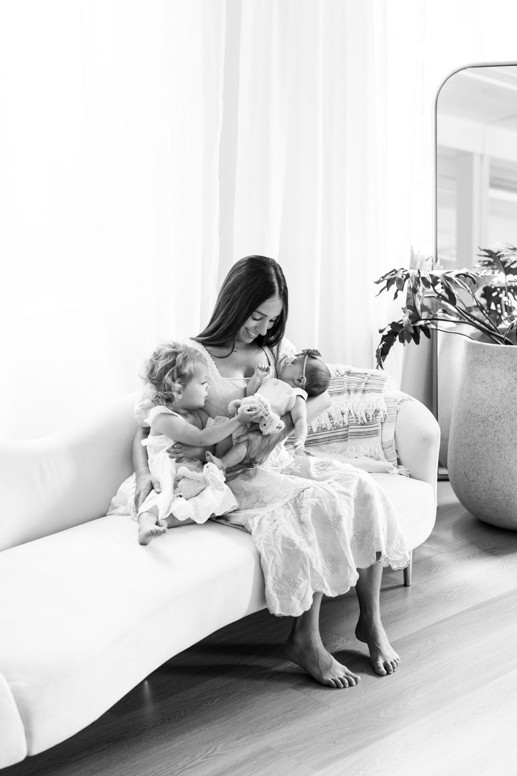 Mother holding two babies during newborn photo session at a studio