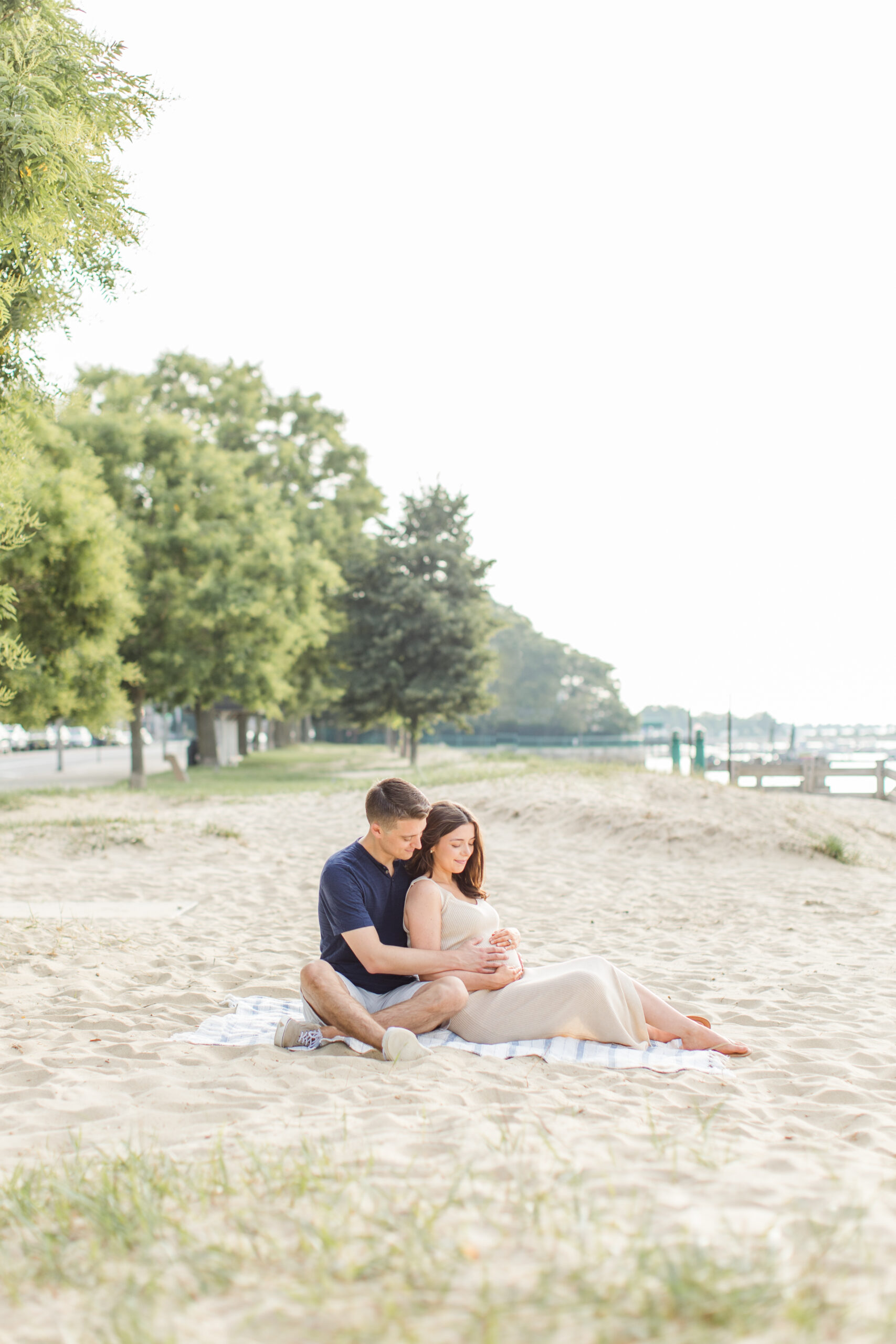 Couple sitting on the beach for maternity photos