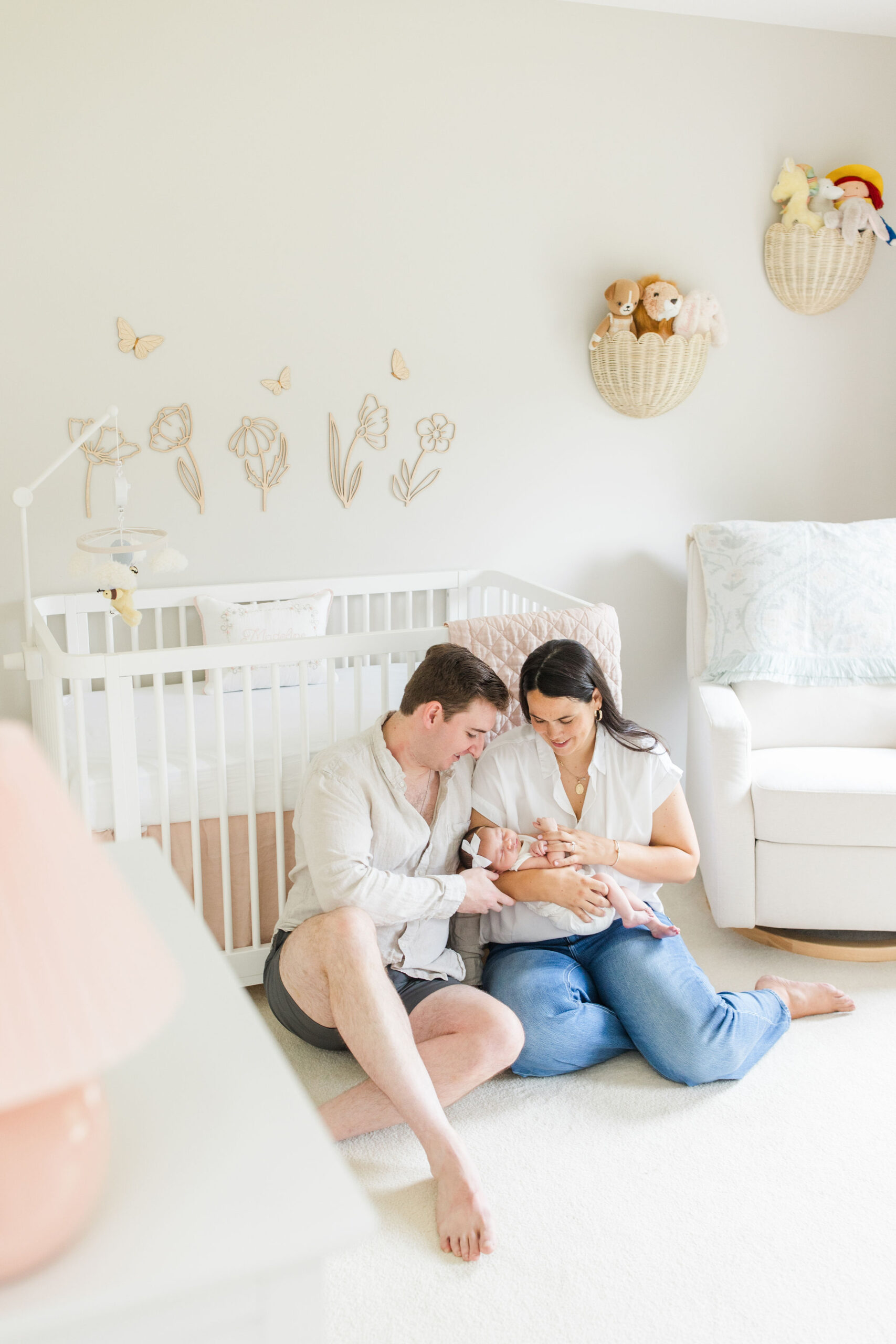 Mother and father holding baby in their at home newborn photoshoot in baby's nursery