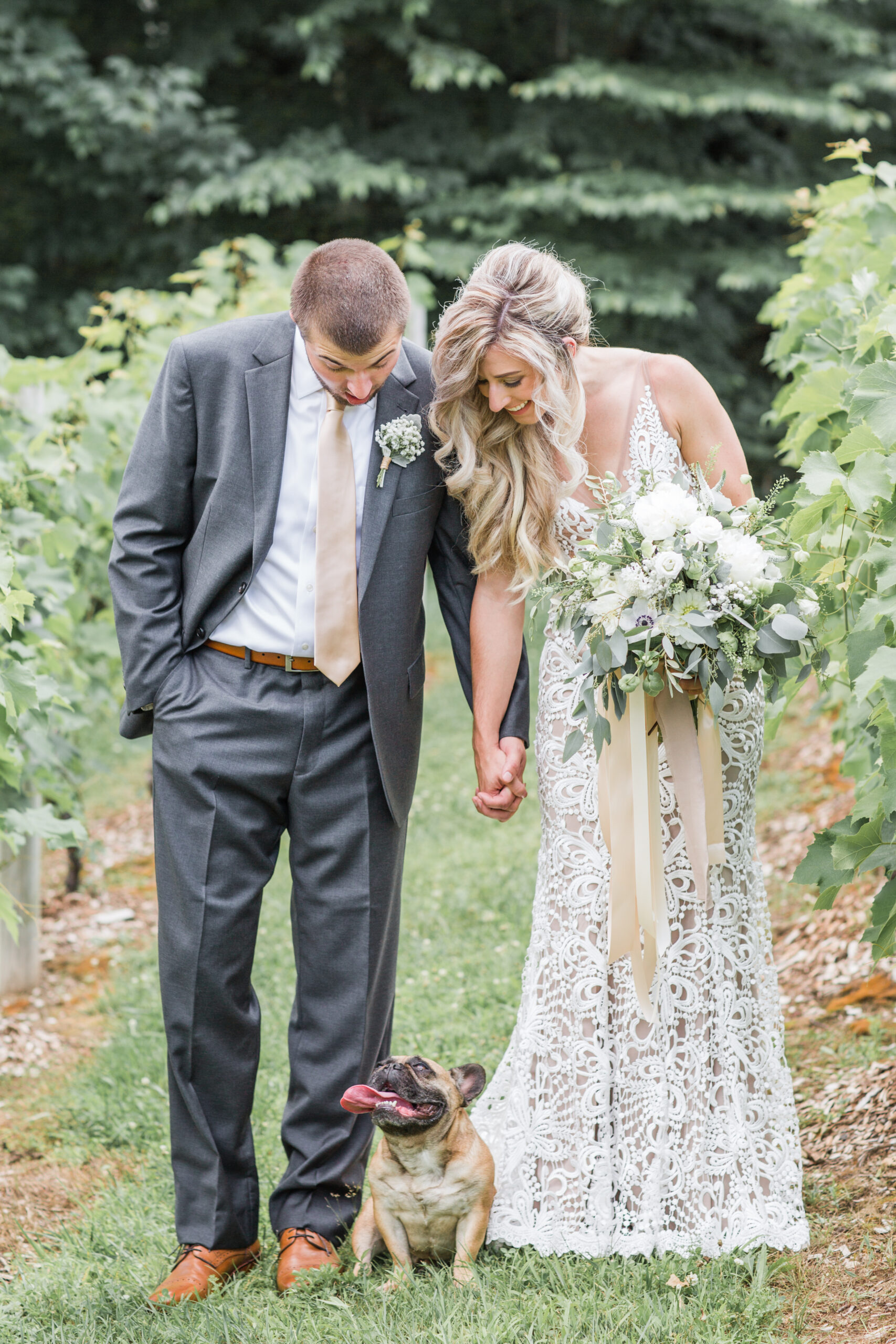 Bride and groom posing with their dog at an outdoor wedding