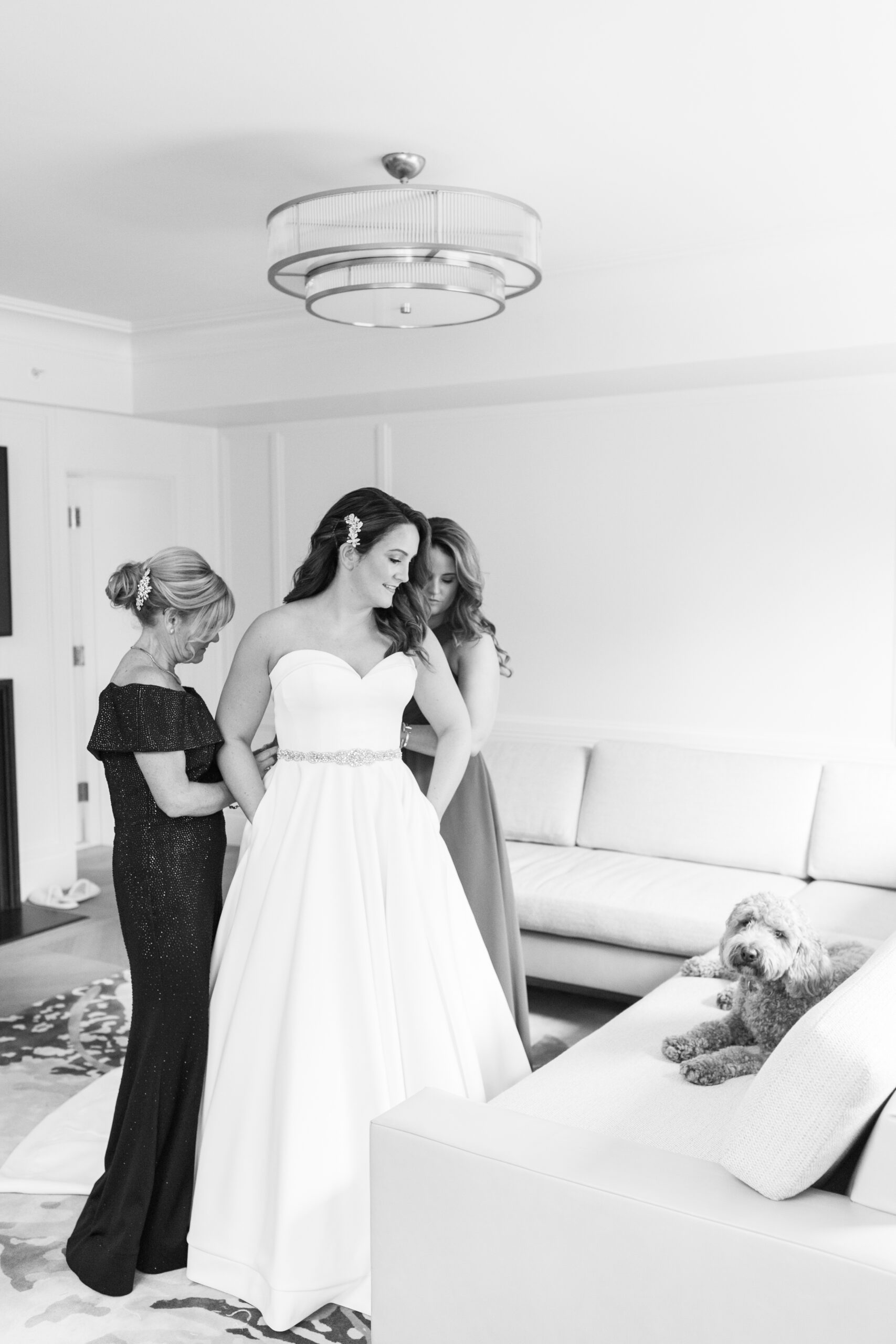 Black and white photo of bride getting ready with her dog at wedding