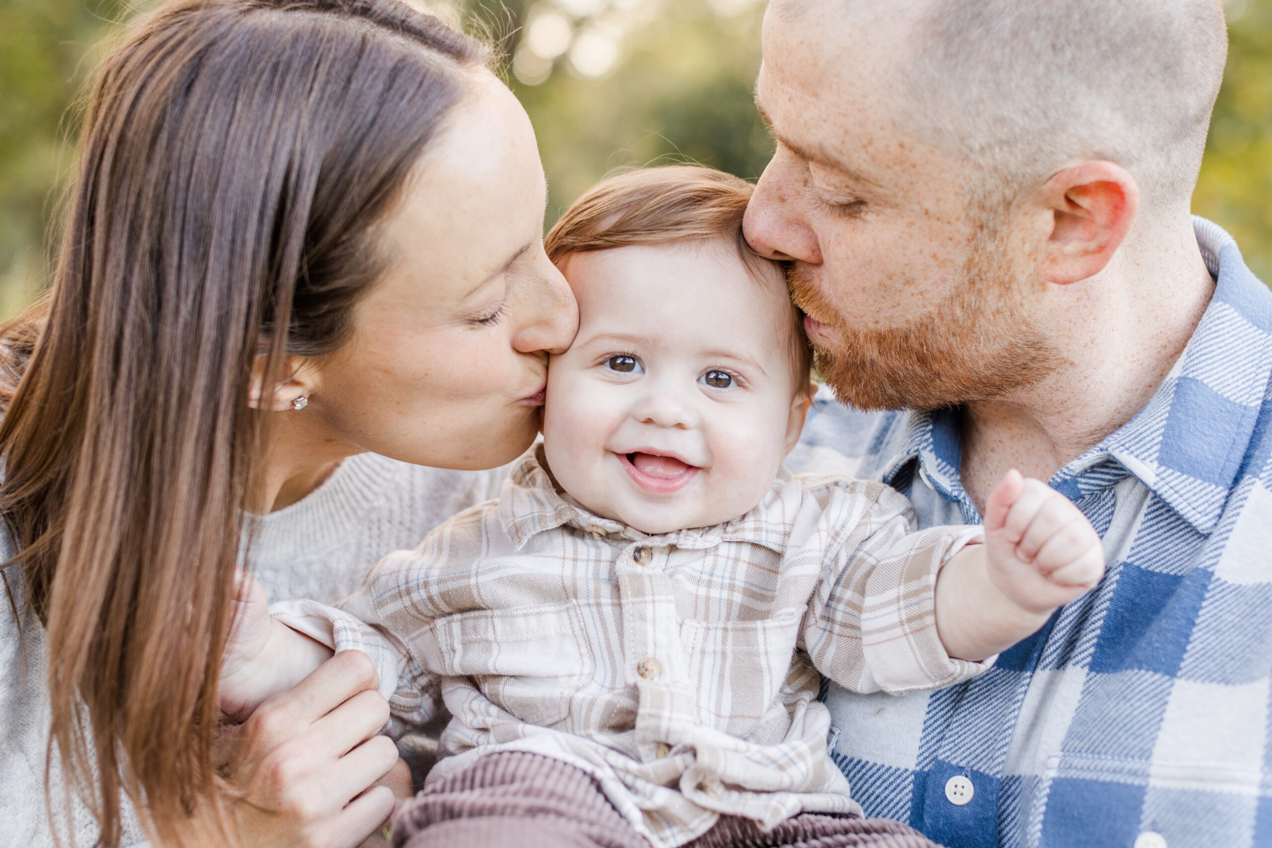 A couple kissing their baby on the head during a fall family photsohoot