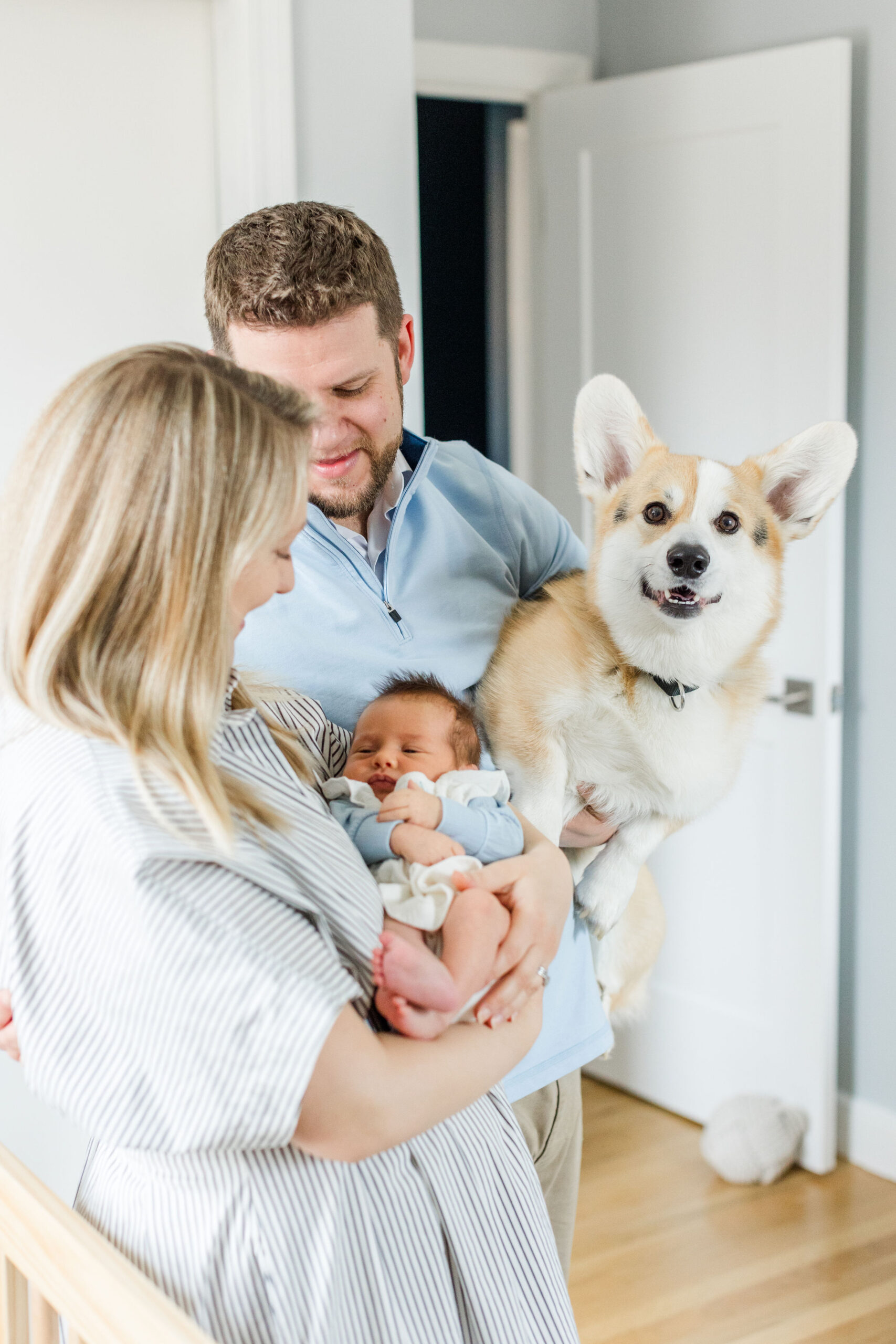 A family holding a baby and dog in a newborn photoshoot