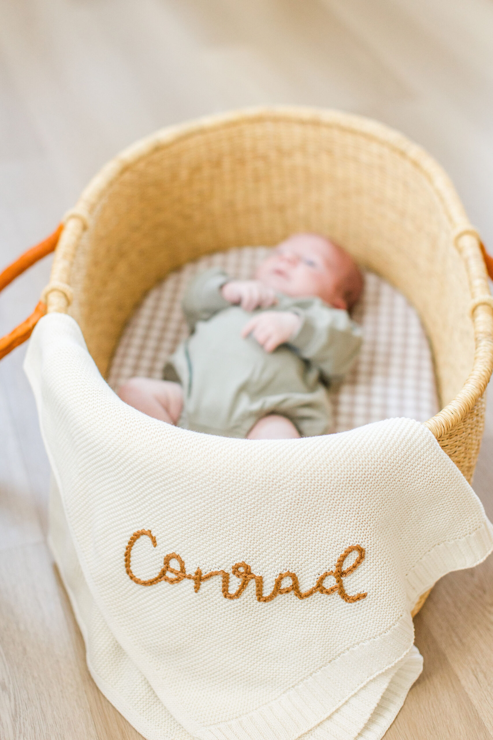 A baby in a basket with a personalized blanket