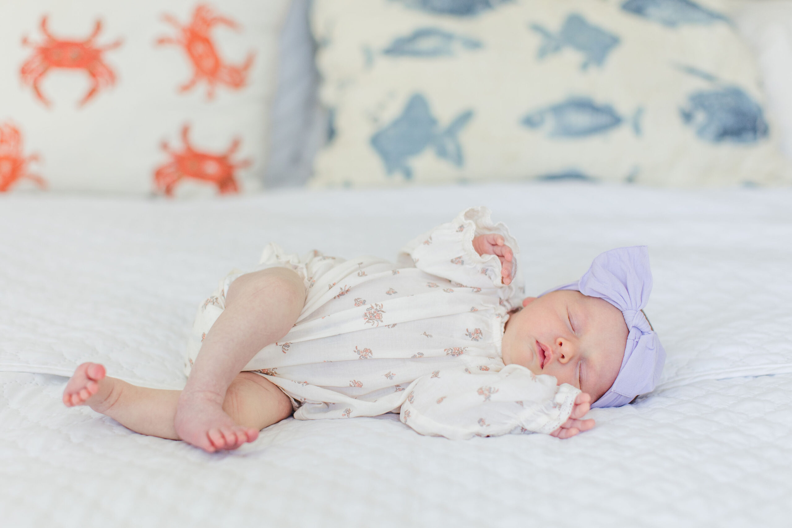 A baby girl lying down with a bow on her head for a newborn photoshoot