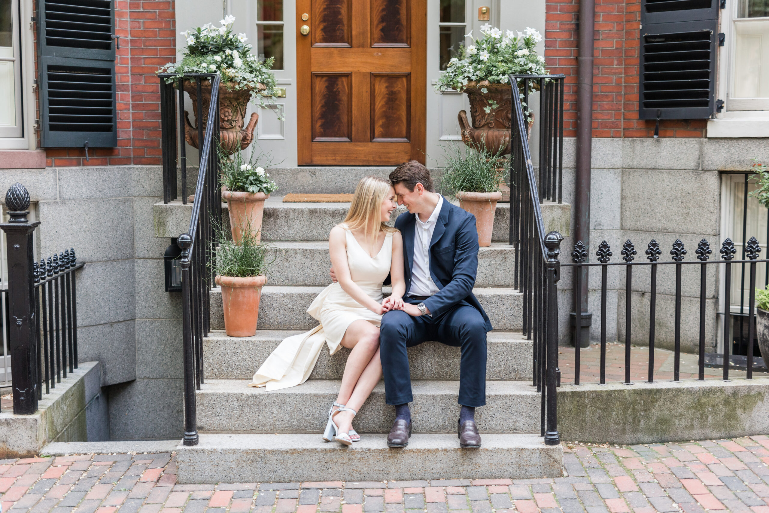 A couple sitting on a stoop at one of my favorite Boston engagement photo locations, Beacon Hill