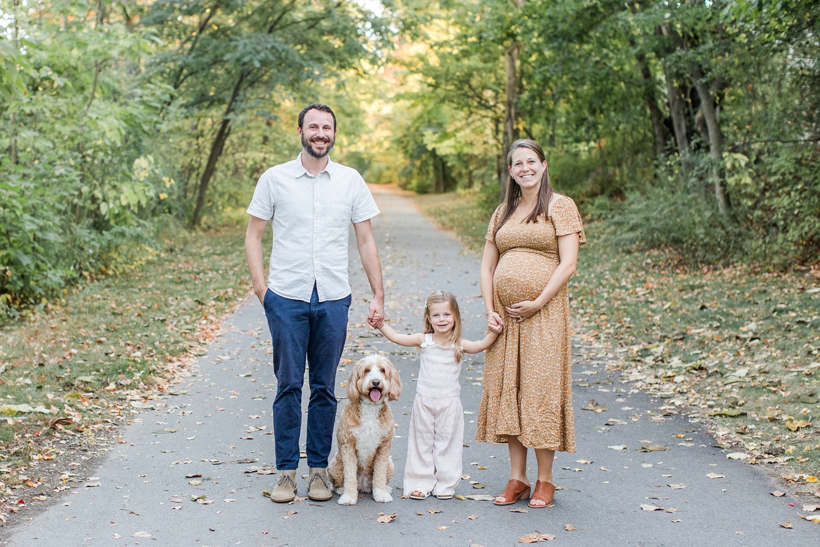Man, woman and baby holding hands during Boston family photos with dogs