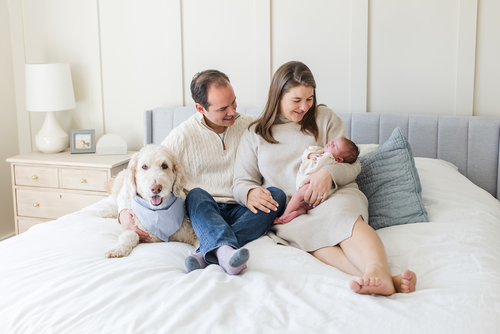 Man and woman with newborn on bed during Boston family photos with dogs