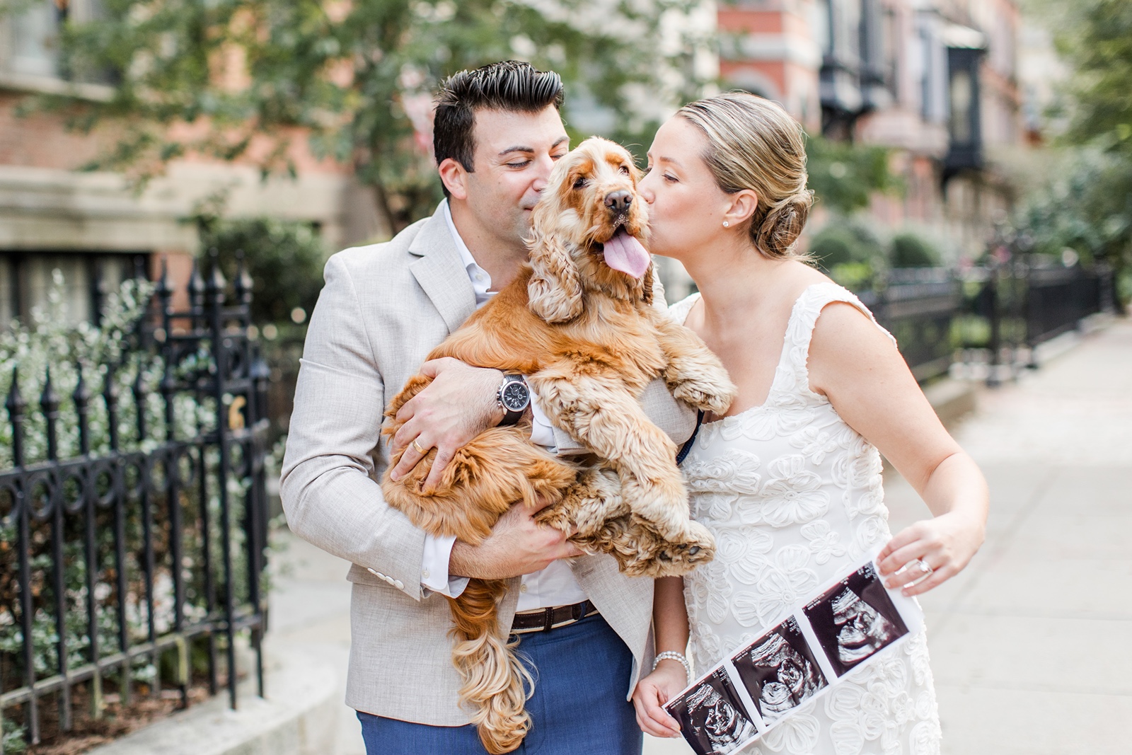 Man and woman kiss dog in Boston during their Boston family photos with dogs