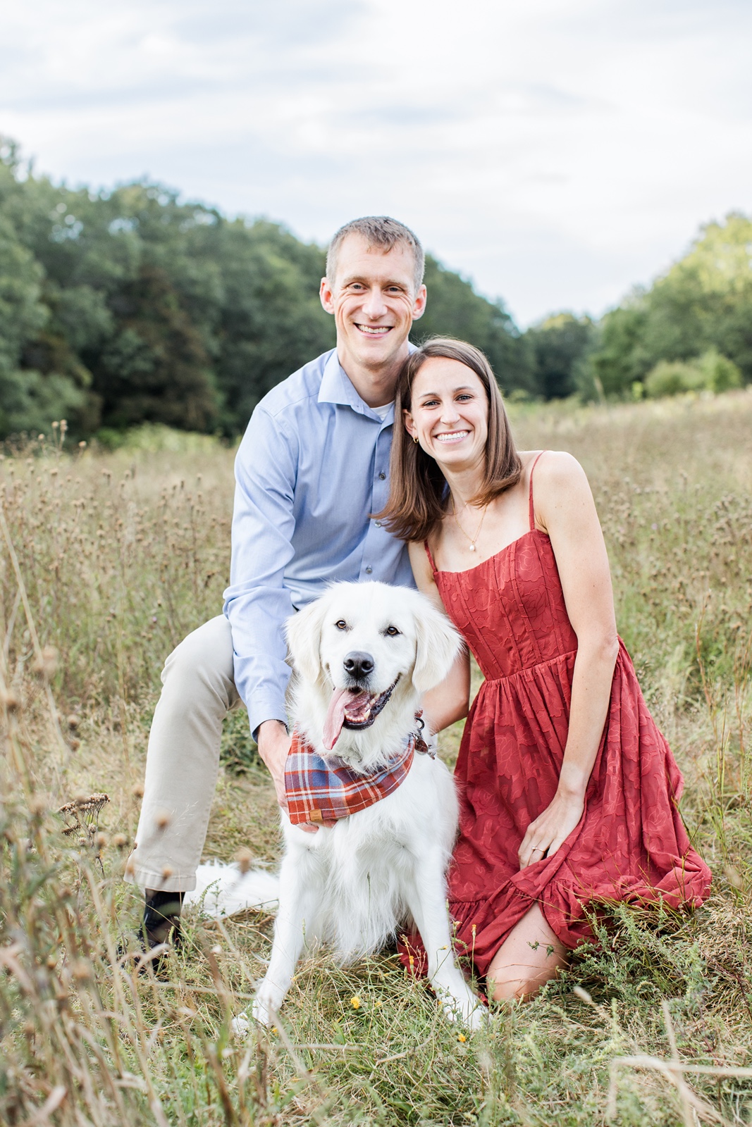 Man and woman pose in field with cream dog during Boston family photos