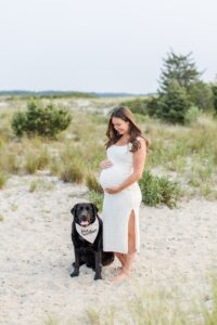 Pregnant woman on beach with dog during Boston family photos with dogs