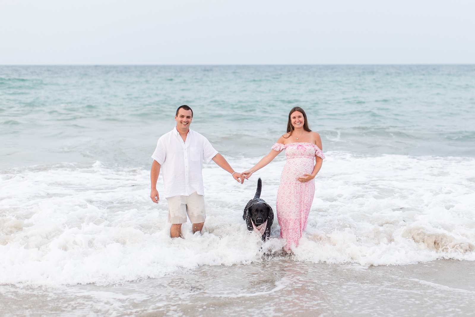 Man and woman with their dog in the ocean during their Boston family photos