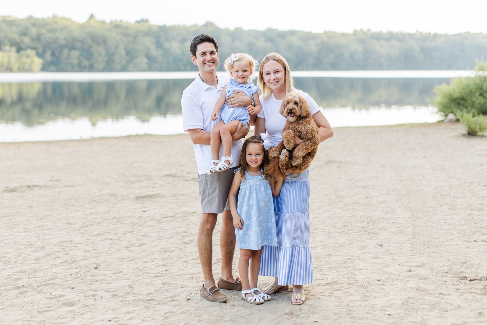 Man and woman hold baby and have toddler and dog during Boston family photos with dogs