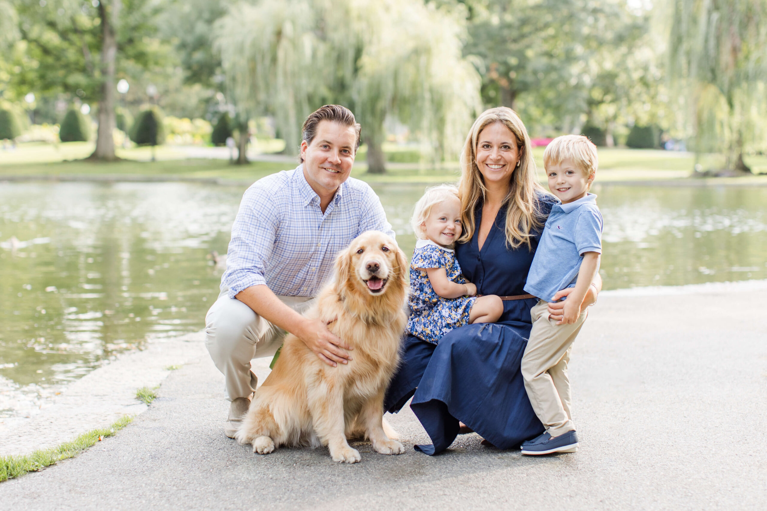 Family posing beside a pond with their golden retriever during an outdoor photo shoot with your dog.